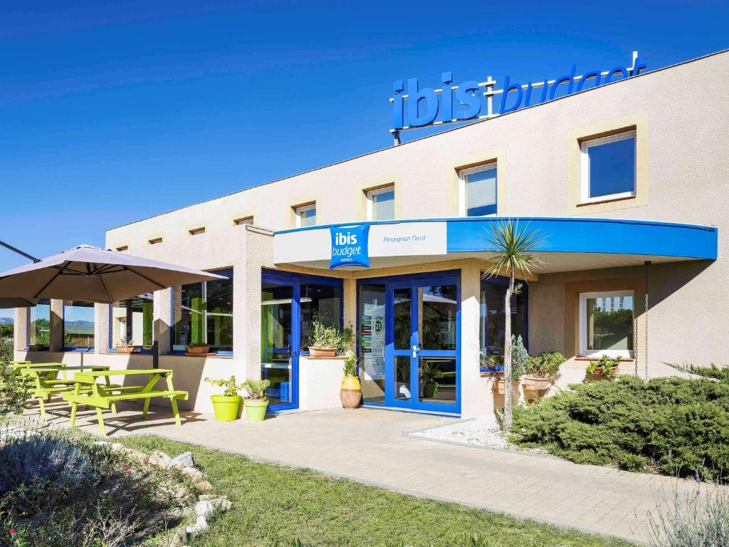 Ibis Budget Perpignan Nord Rivesaltes في ريفسالت: فندق يوجد طاولات وكراسي خارجه