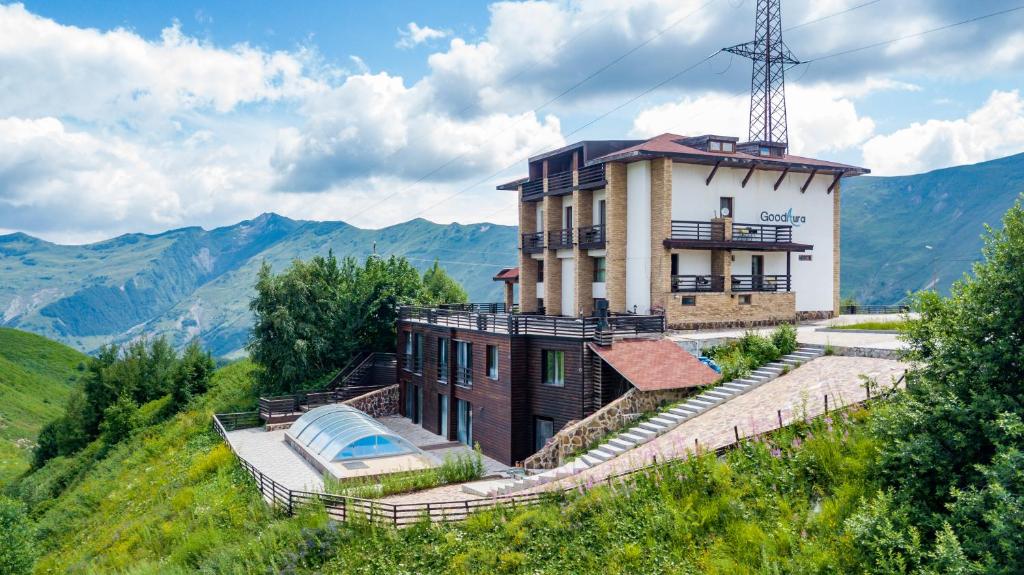 una casa en la cima de una colina con montañas en el fondo en Hotel GoodAura, en Gudauri