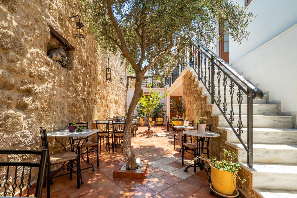 un patio con mesas, sillas y un árbol en Cava d'Oro, en Rodas