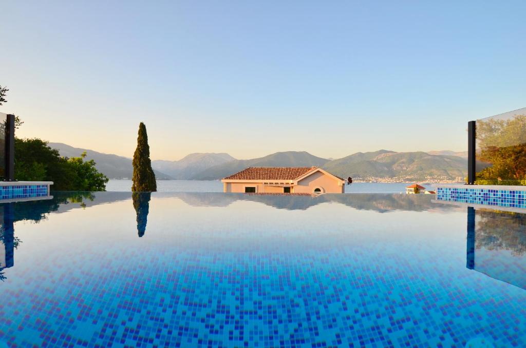 a swimming pool with a house in the middle of the water at Leut Stone Residence in Tivat