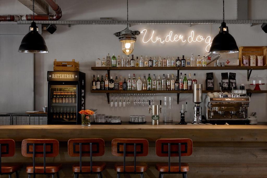 eine Bar mit einer Theke und einigen Barhockern in der Unterkunft Kröger by Underdog Hotels in Hamburg