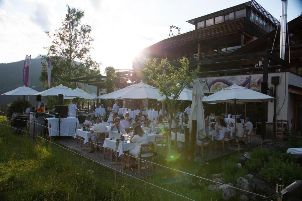 a group of people sitting at tables with umbrellas at Holzhotel Forsthofalm in Leogang