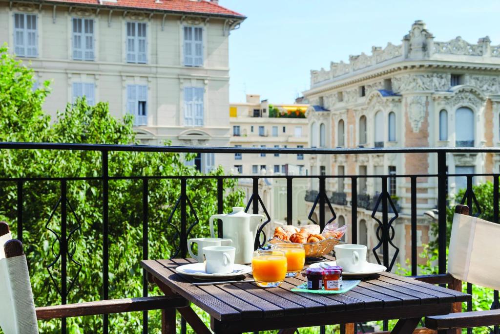 einen Tisch mit Speisen und Orangensaft auf dem Balkon in der Unterkunft La Malmaison Nice Boutique Hôtel in Nizza