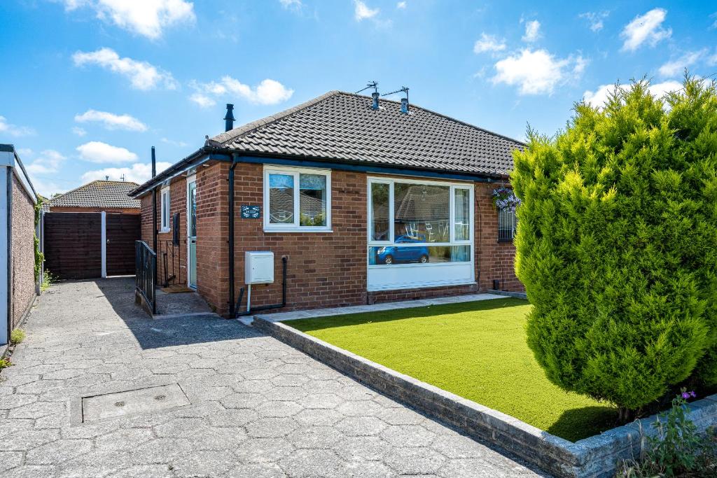a brick house with a lawn in front of it at Buttercup Bungalow in Blackpool in Blackpool