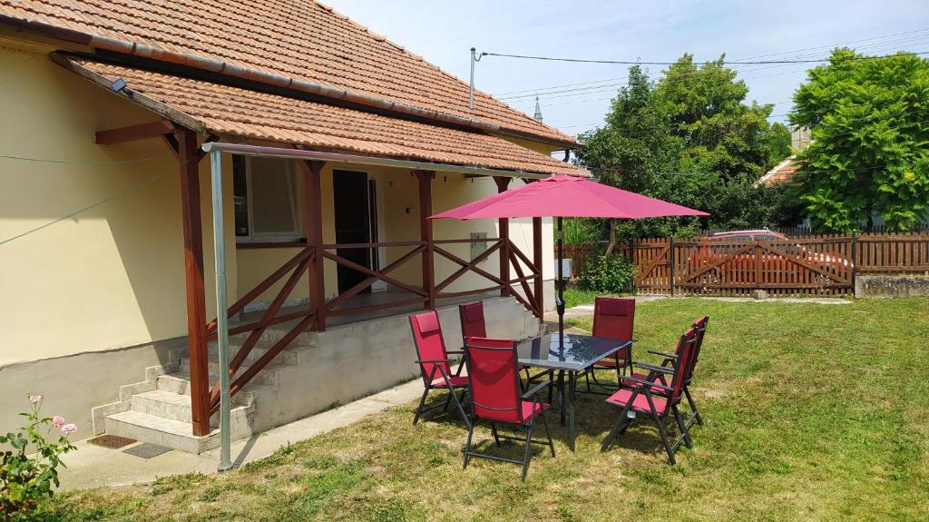 a table and chairs with a pink umbrella in a yard at Öregakác Vendégház in Tiszaladány