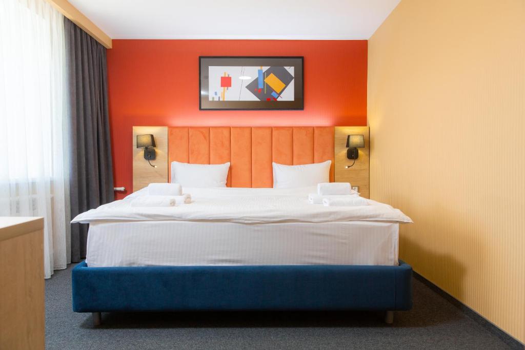 1 dormitorio con 1 cama grande y pared de color naranja en Отель KOKSHETAU en Kokshetau