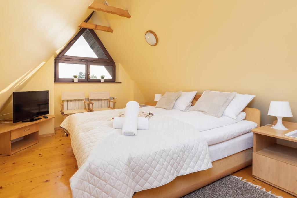 a bedroom with a large white bed and a tv at Apartment Wojciecha Brzegi Zakopane by Renters in Zakopane