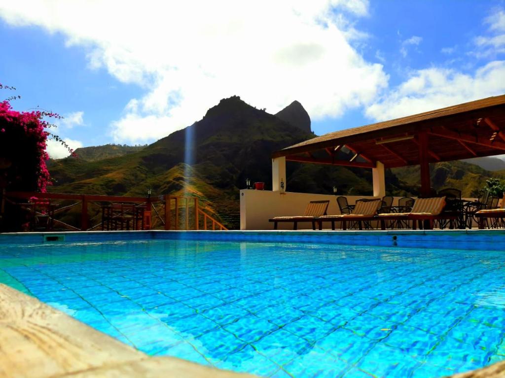a large swimming pool with a mountain in the background at Pedracin Village in Ribeira Grande