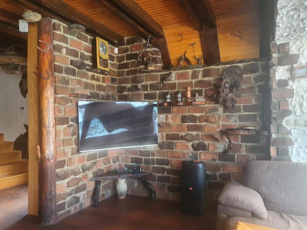 eine Ziegelwand mit einem Flachbild-TV in der Unterkunft Vikendica Blidinje Čarobna kuća in Tomislavgrad