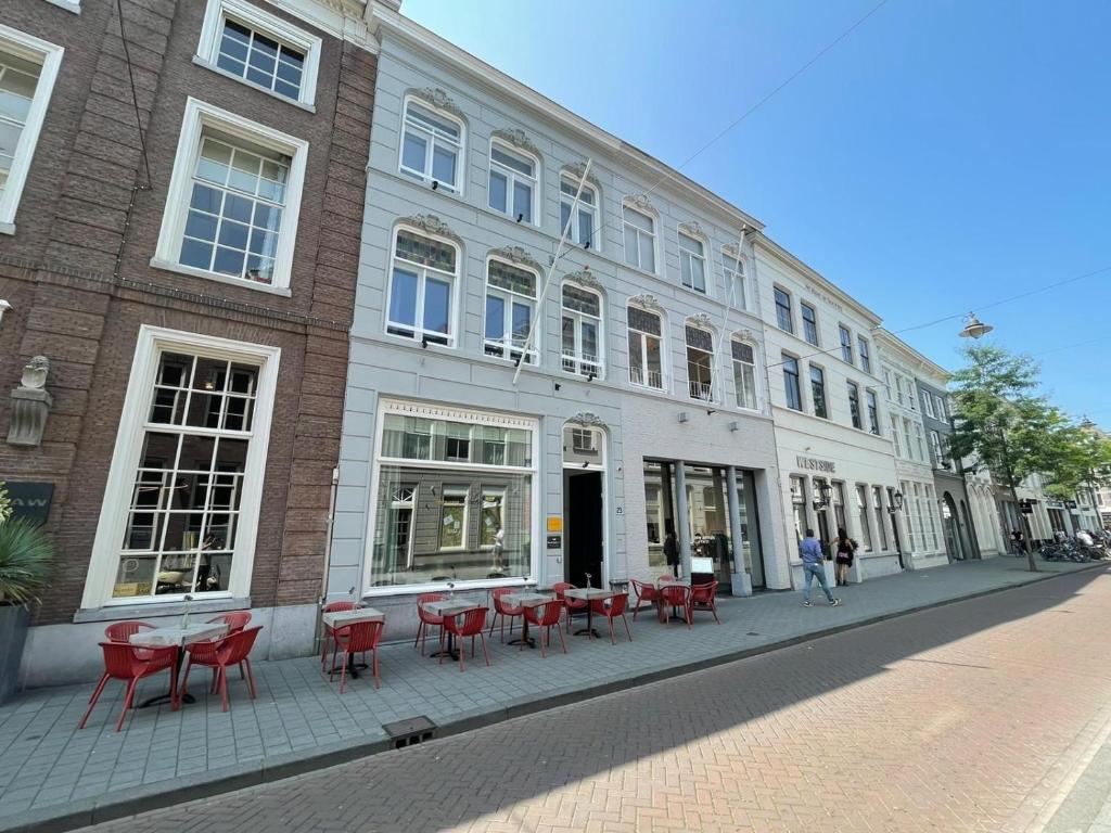 um edifício com mesas e cadeiras vermelhas numa rua em Bossche Suites No2 - Verwersstraat em Den Bosch