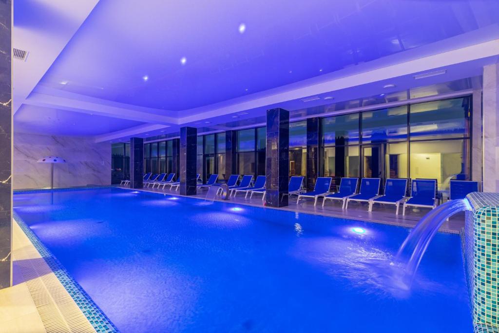 a large swimming pool with blue chairs in a building at Villa Elena SPA & Resort in Bukovel