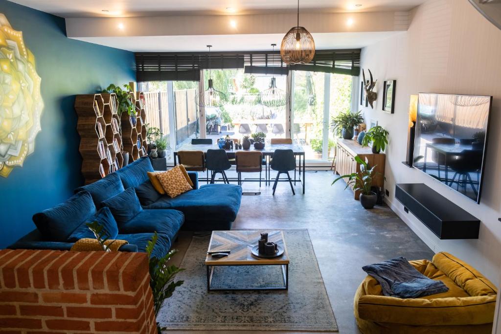 uma sala de estar com um sofá azul e uma mesa em Comfort en luxe & ontspan dichtbij duin, strand en bos em Egmond aan den Hoef