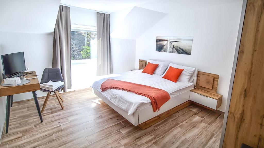1 dormitorio con cama con almohadas de color naranja y escritorio en Zelena Oaza, en Zgornja Kungota