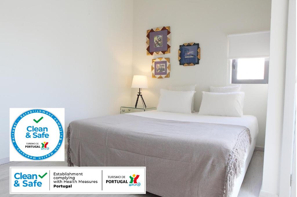 リスボンにあるVila Santa Marinhaの白いベッドルーム(ベッド1台付)、清潔で安全な看板が備わります。