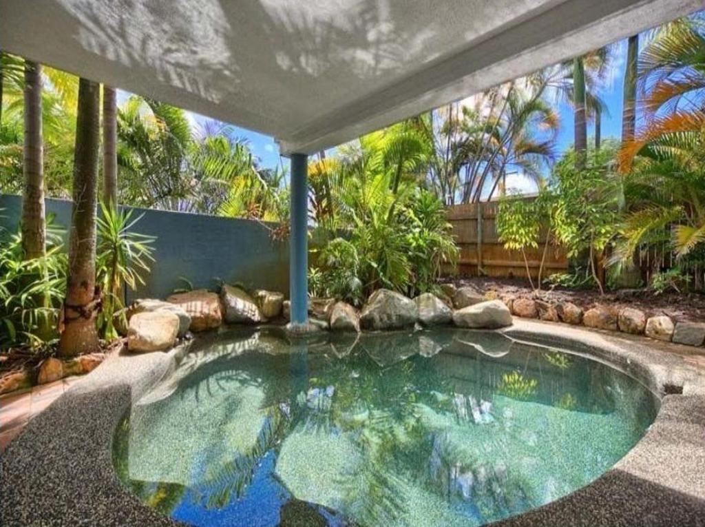 a swimming pool in a garden with a large umbrella at Cairns Sunshine Lodge in Cairns North