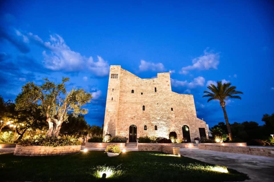 un gran edificio de piedra con palmeras por la noche en Hotel Torre Domini, en Giovinazzo