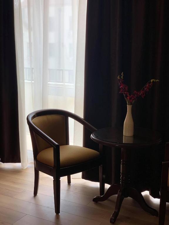 a chair and a table and a vase with flowers on it at Pensiunea Junior in Cluj-Napoca