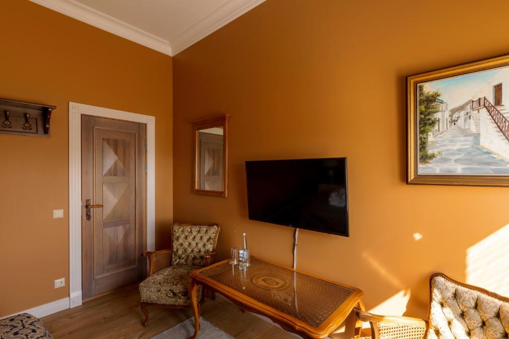 ein Wohnzimmer mit einem Tisch und einem Flachbild-TV in der Unterkunft Boutique Apartment Virkas muiža in Kuldīga