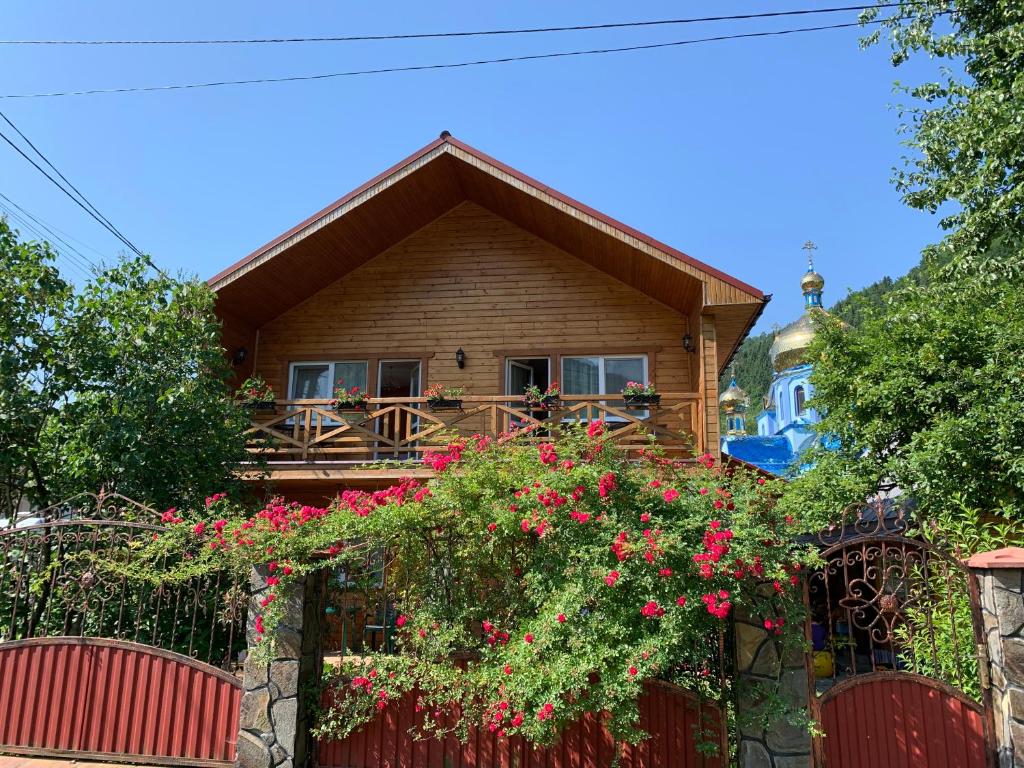 a wooden house with a fence and flowers at ZarinSki in Kvasy