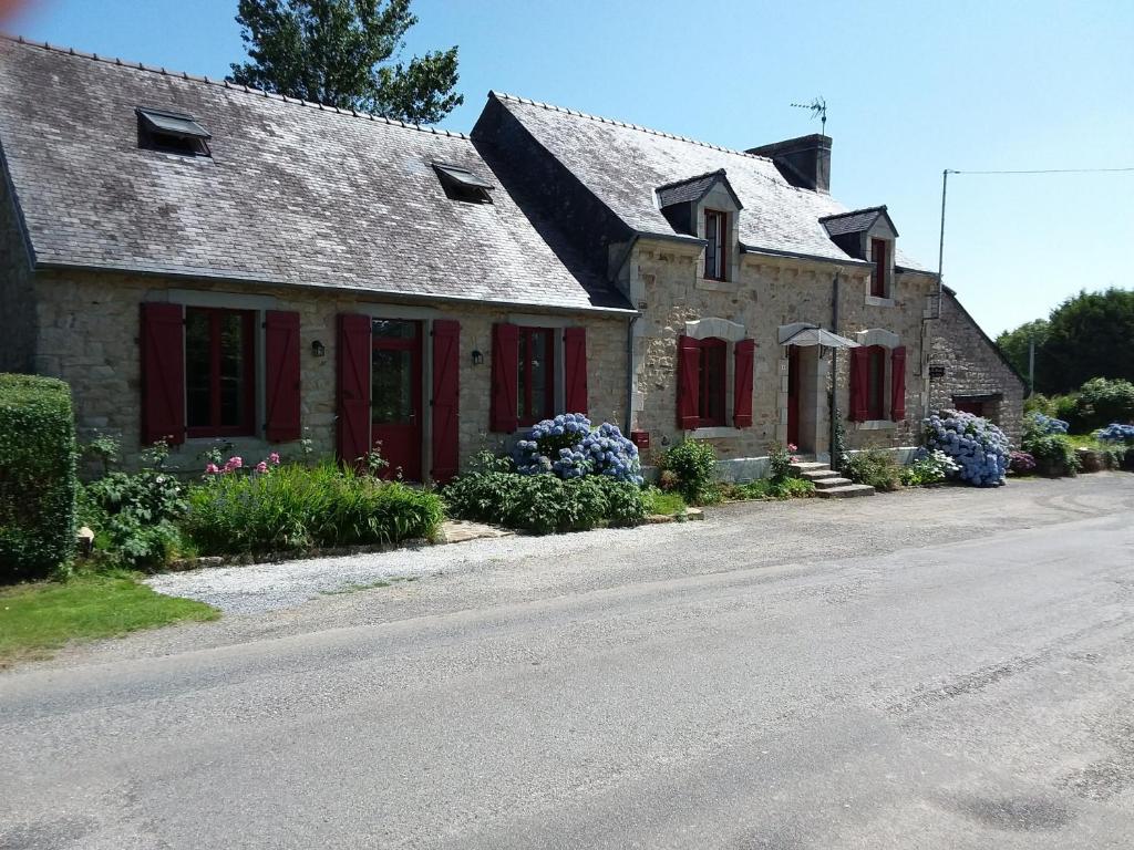 Les chambres de Marie في Le Saint: منزل حجري ذو مصاريع حمراء على شارع