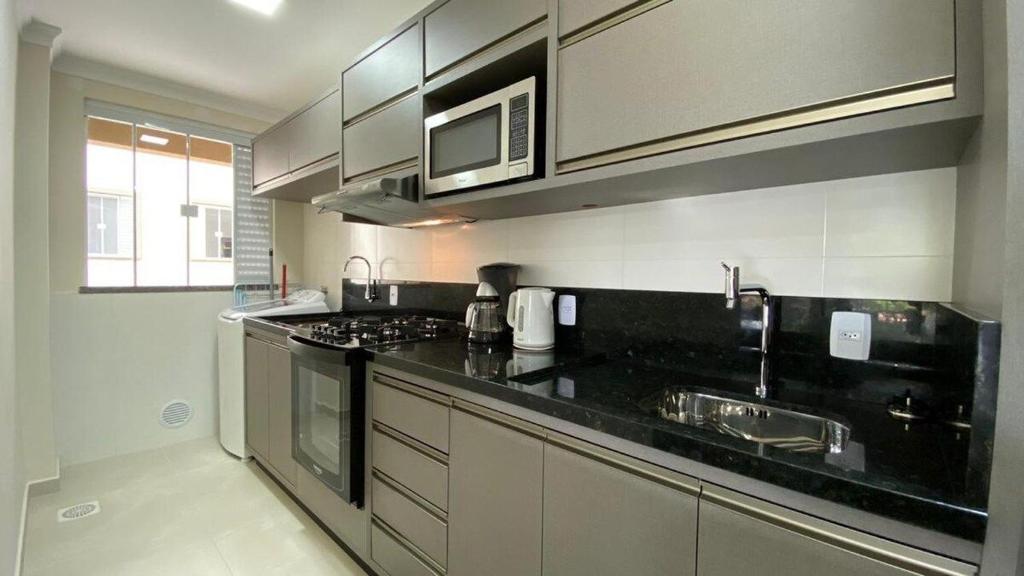 una cucina con piano di lavoro nero e lavandino di Manchester 106 A · Lindo e novíssimo Apartamento na praia Bombas. a Bombinhas