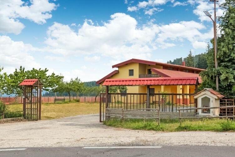 una casa amarilla con techo rojo y valla en Villa Paradiso en Parenti