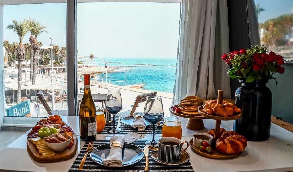 einen Tisch mit Speisen und Wein sowie Meerblick in der Unterkunft COSea Living: SeaSide Deluxe Suite in Harbour 107B in Paphos City
