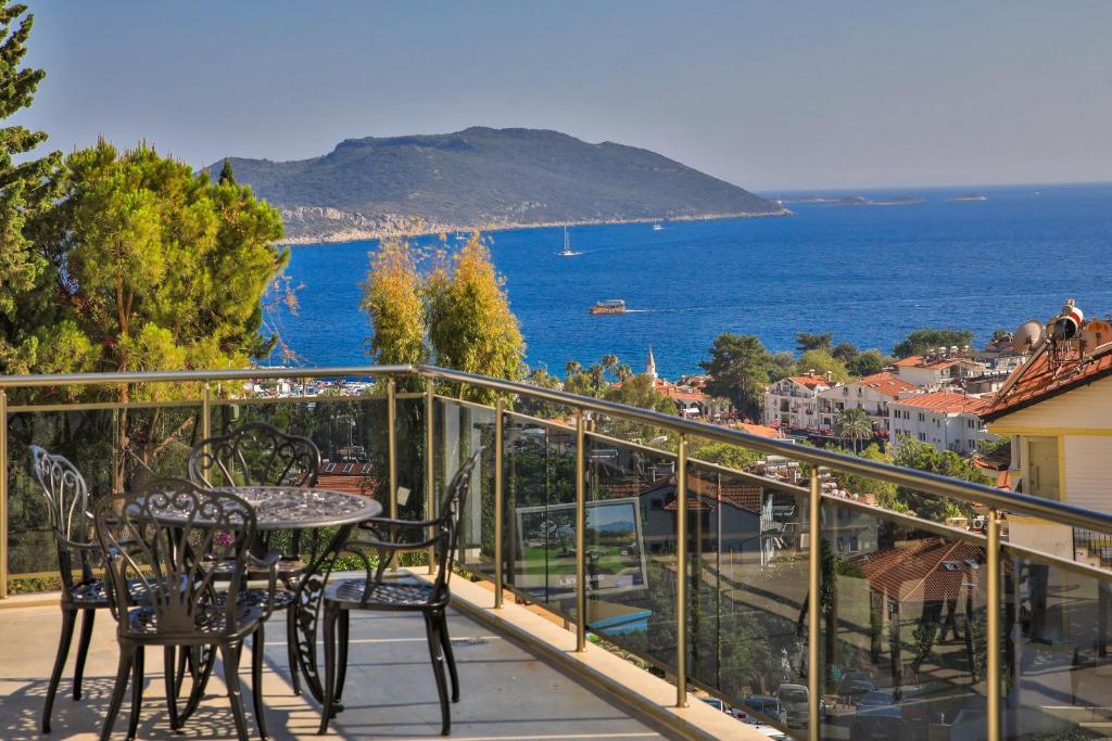balcón con mesa, sillas y vistas al océano en Happy Kaş Apart, en Kas