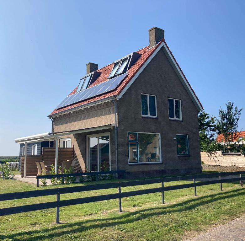 Vissers Huus Hollum Ameland في هولوم: منزل على السطح مع لوحات شمسية