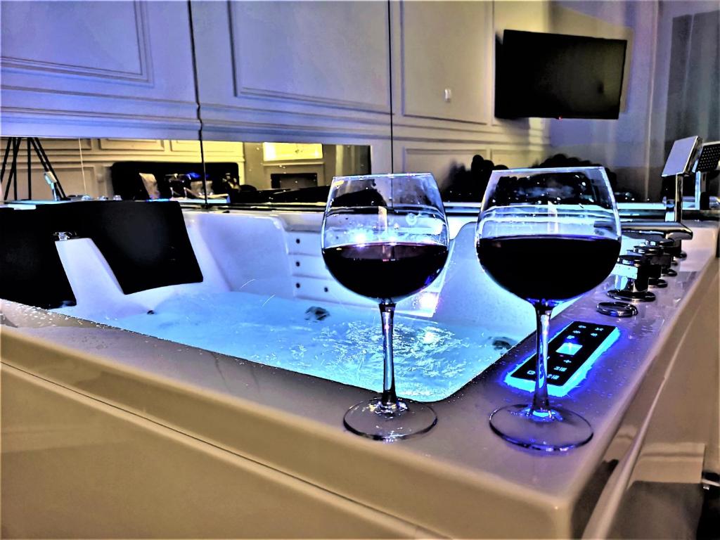 two glasses of red wine sitting on a bar at Luxury Jacuzzi Apartment in Krakow