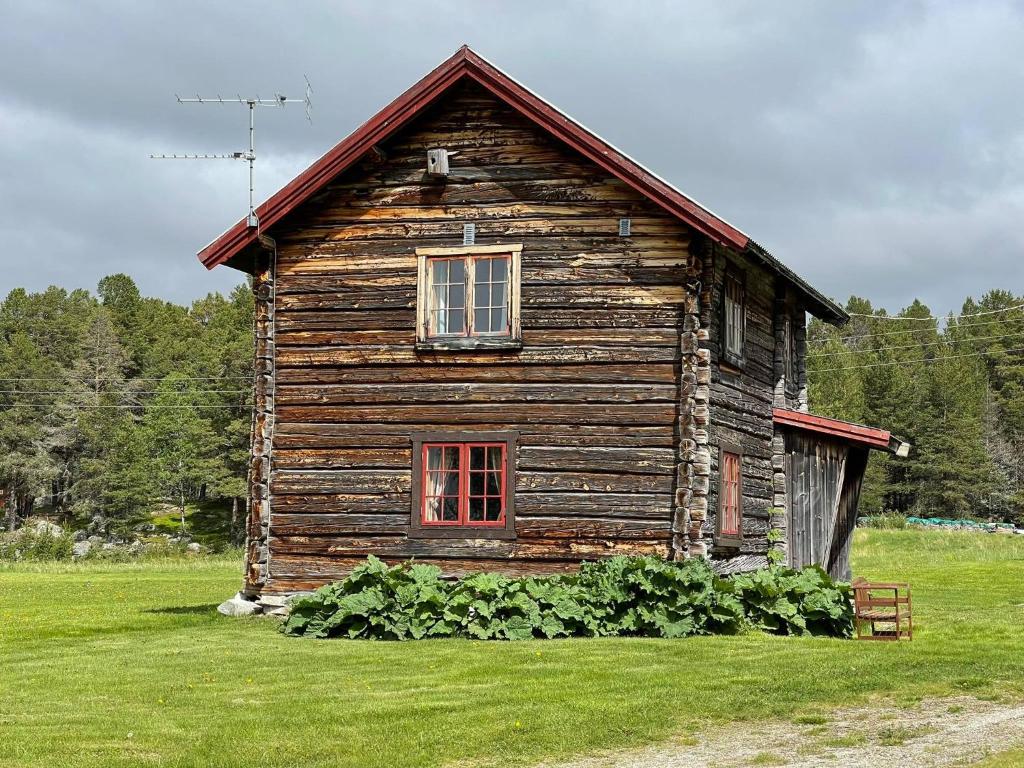 una vieja casa de madera en un campo de hierba en Gammelstua ved Femund en Elga