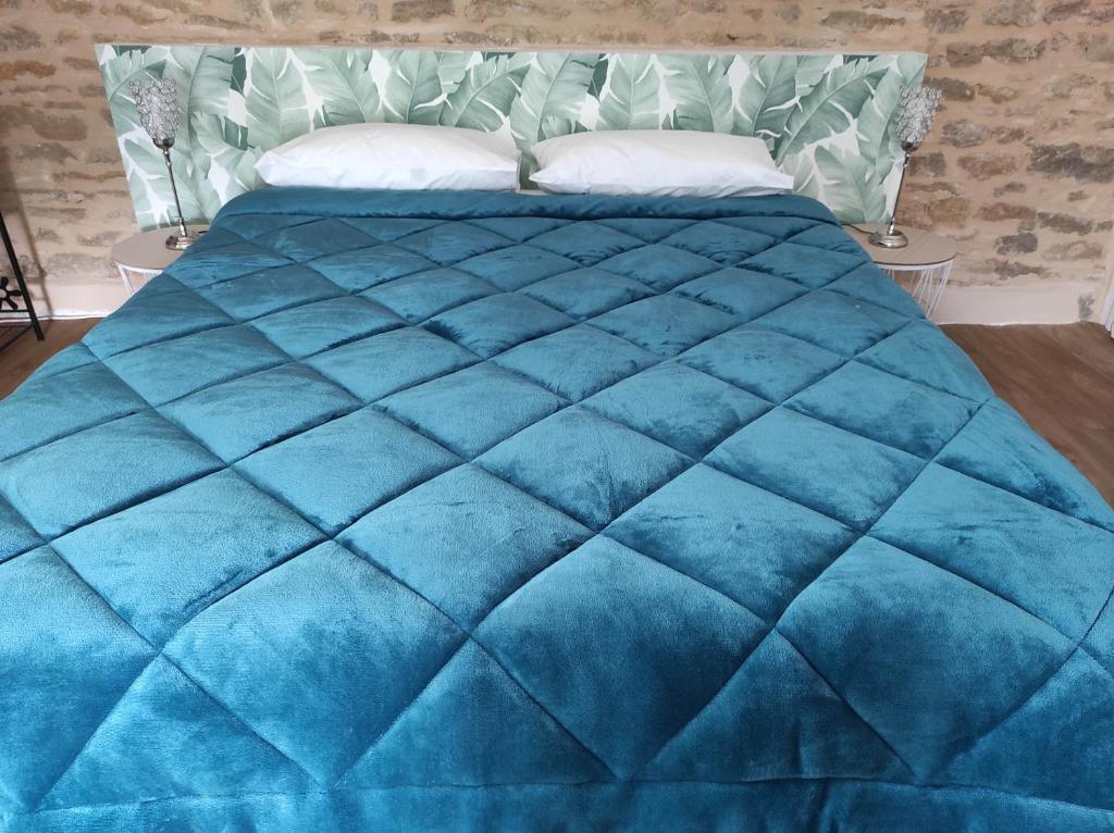a blue comforter on a bed in a room at Appartement Oingt - Les Meublés des Pierres Dorées in Theizé
