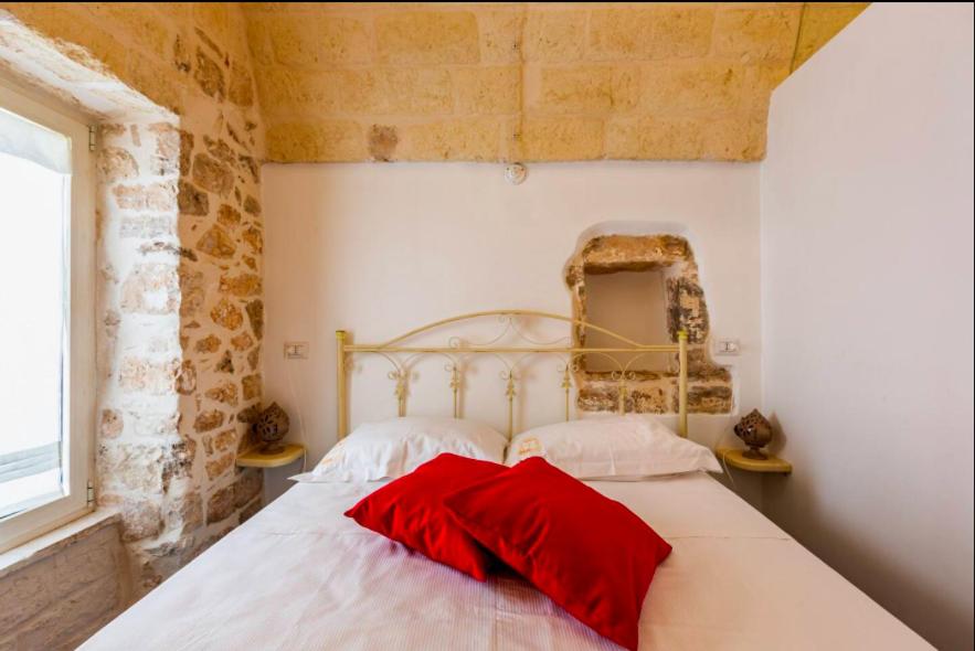 una camera da letto con un letto con cuscini rossi di La Finestra Dimora Charme a Ceglie Messapica