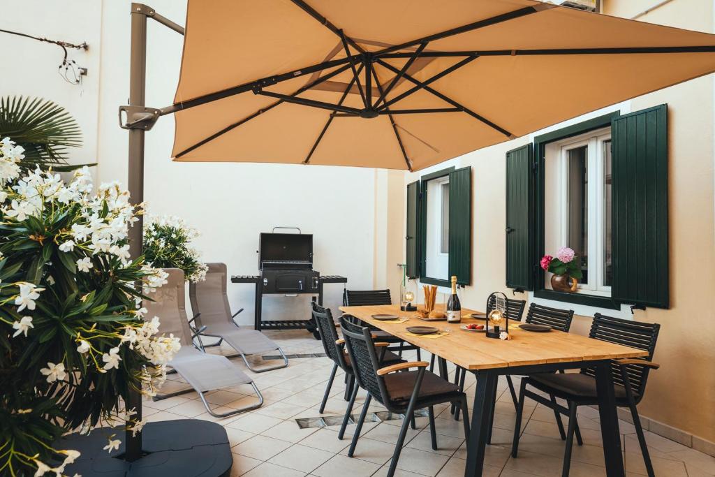 eine Terrasse mit einem Holztisch, Stühlen und einem Sonnenschirm in der Unterkunft Apartment Park Piran in Piran