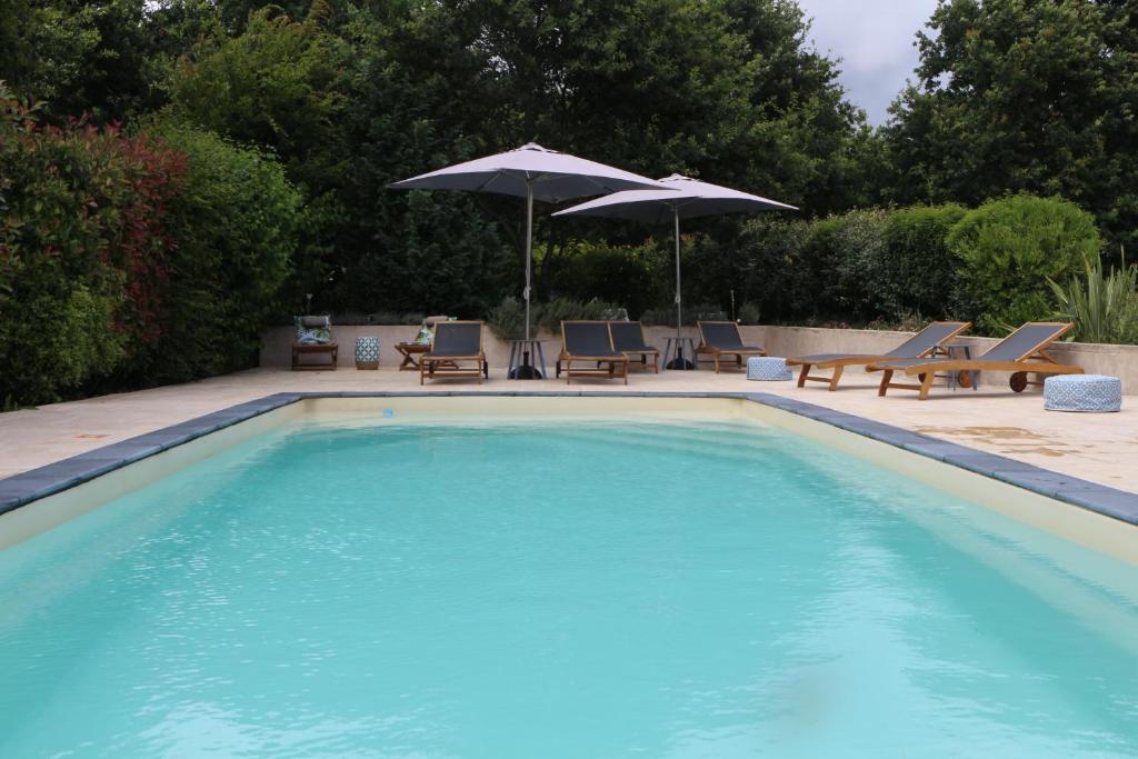une grande piscine avec chaises et parasols dans l'établissement Le Chant des Pierres - Entre Terre et Mer, à Pornic