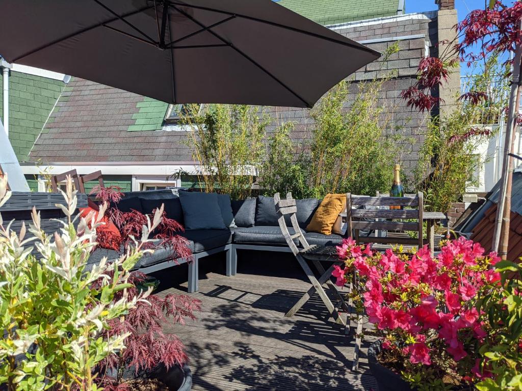 a patio with a couch and an umbrella and flowers at StoreStay DamSquare in Amsterdam