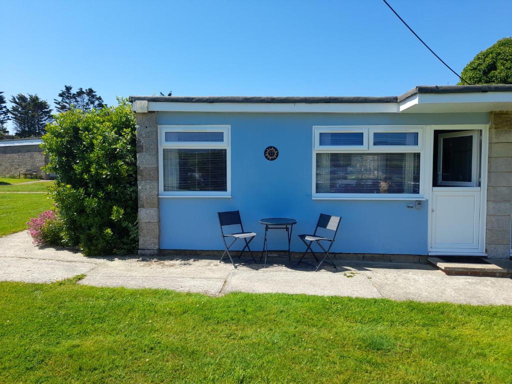 a blue house with two chairs and a table in front of it at Sunrise 77 Sandown Bay Holiday Centre Generous Ferry Saving! in Sandown