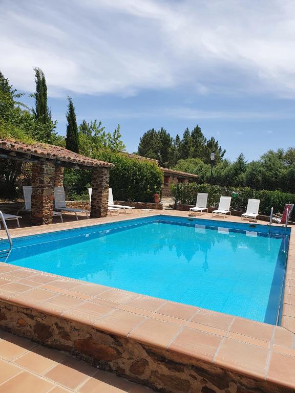 una gran piscina con sillas en El Jiniebro Turismo Rural, en Valencia de Alcántara