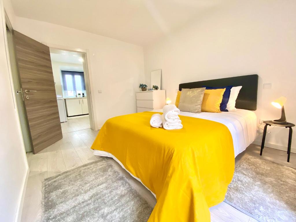 a bedroom with a large bed with a yellow blanket at BrightHouse - Modern Apartments in Sítio Nazaré in Nazaré