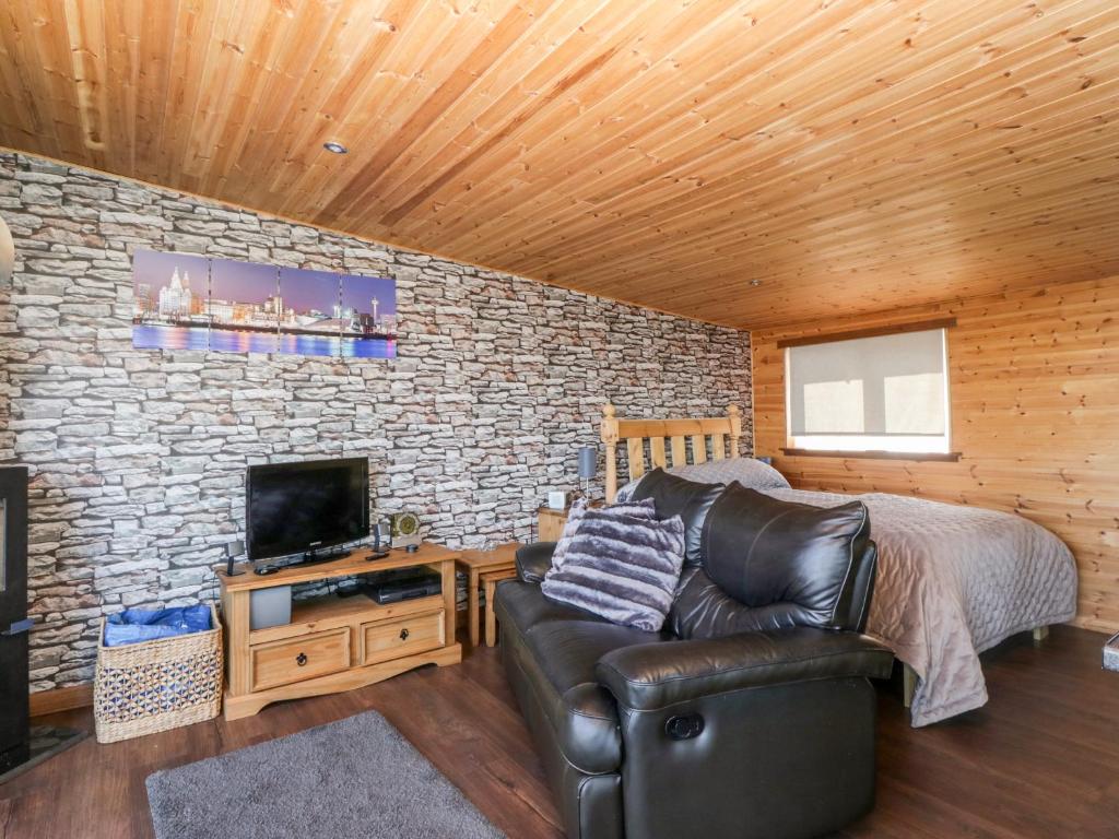 a living room with a leather couch and a television at Blackbrae Cabin in Coatbridge