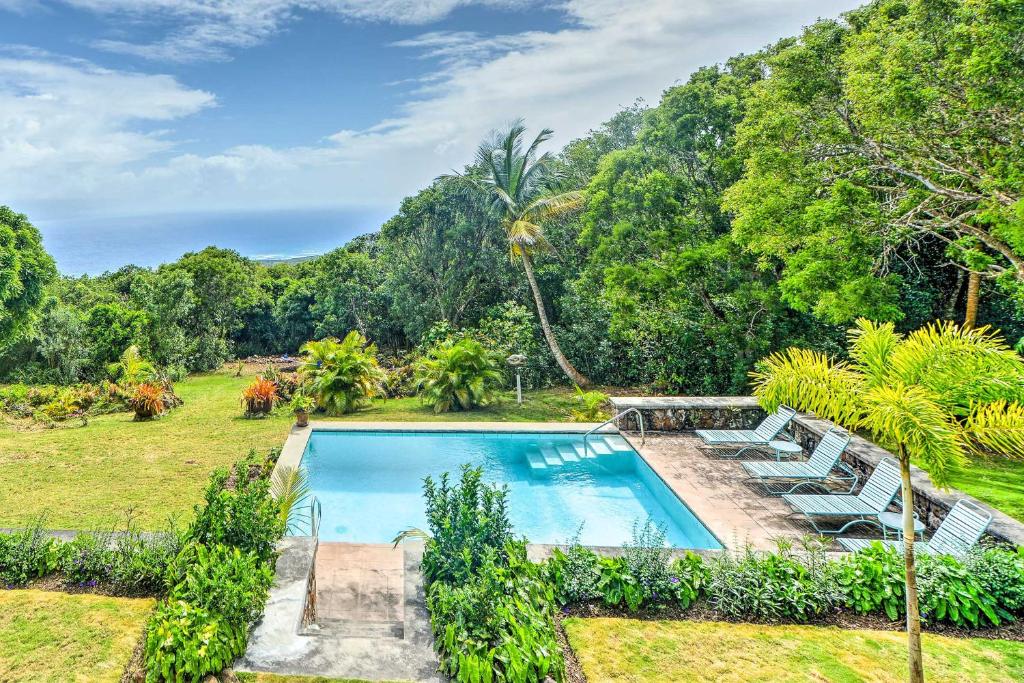 an image of a swimming pool with chairs and trees at Nevis Home with Pool, Stunning Jungle and Ocean Views! in Gingerland