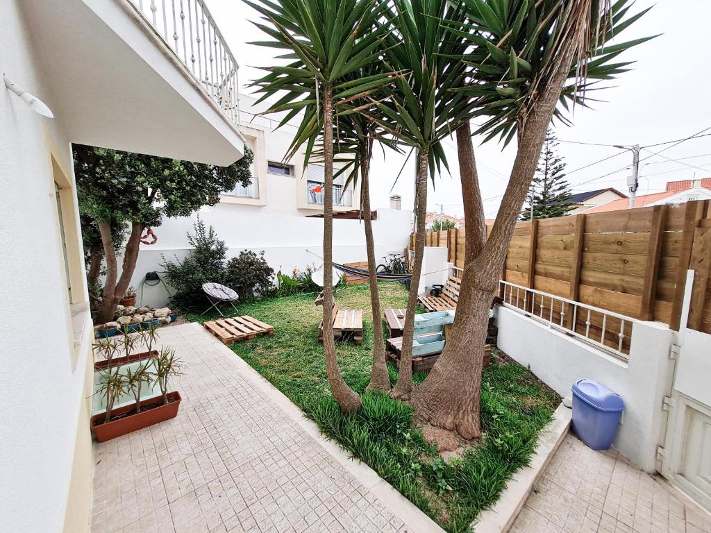 a courtyard with two palm trees and a fence at Cloud to Chill Surfhouse Baleal in Ferrel