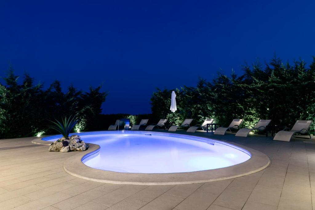 a swimming pool with chairs and a blue background at B&B Villa Bisceglia in Monte SantʼAngelo