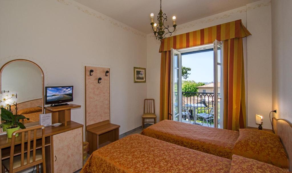 a hotel room with two beds and a balcony at Hotel Villa Ombrosa in Marina di Pietrasanta