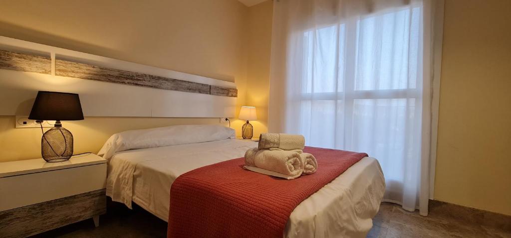 Habitación de hotel con cama con silla y ventana en Puerto Fino Apartamentos, en Almerimar