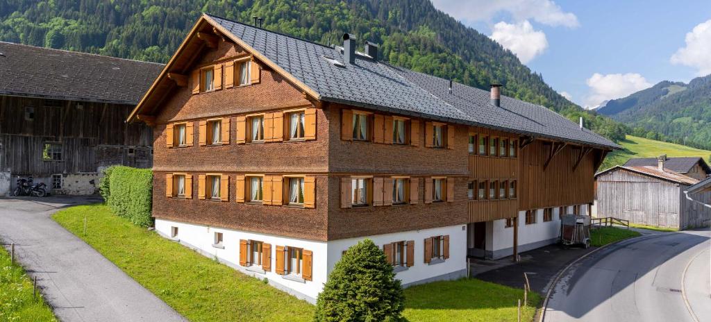 a large wooden building with windows and a mountain at Ferienbauernhof Berlinger in Au im Bregenzerwald
