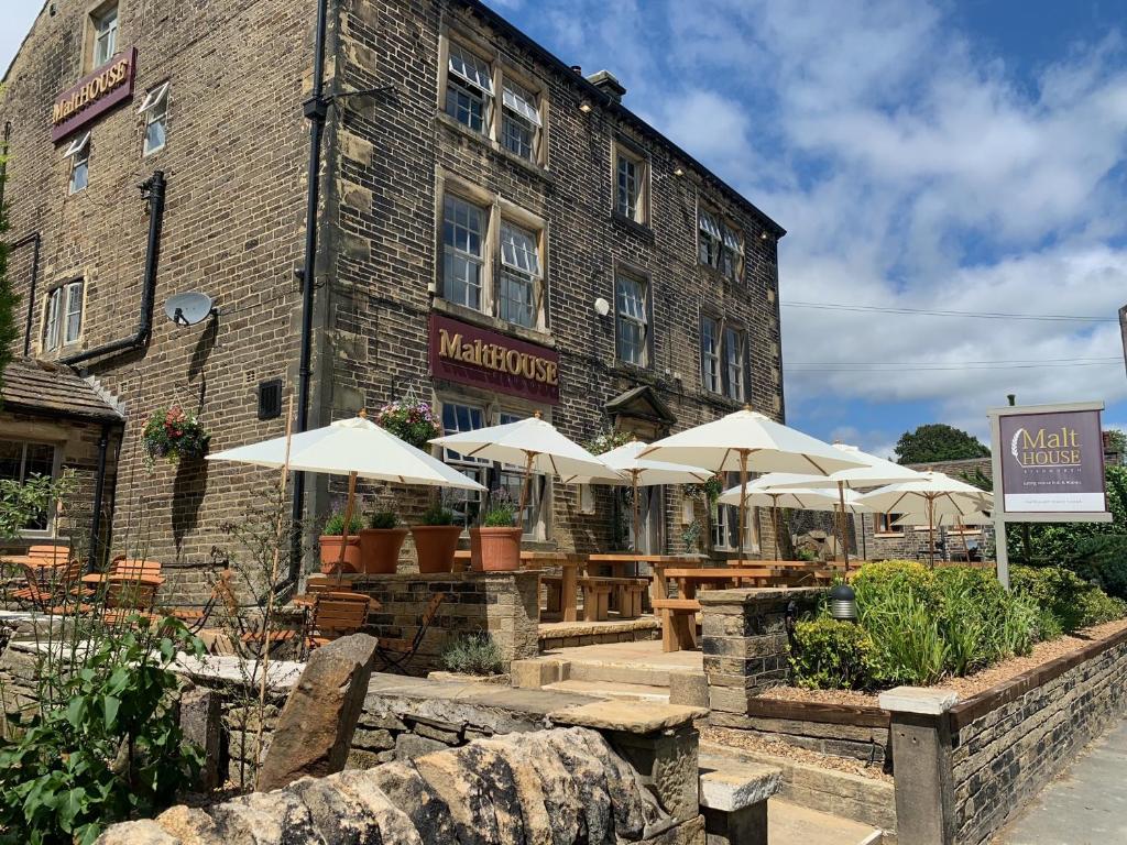 a restaurant with tables and umbrellas in front of a building at The Malthouse in Halifax