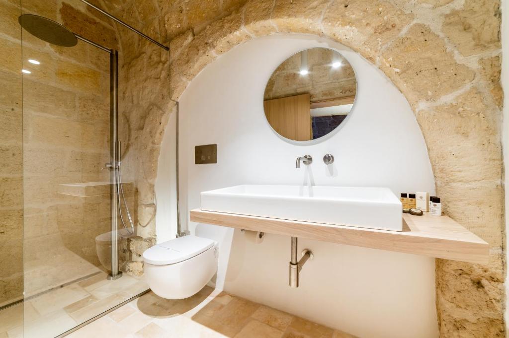 a bathroom with a sink and a toilet and a mirror at Tre Archi Suite & Relais in Polignano a Mare