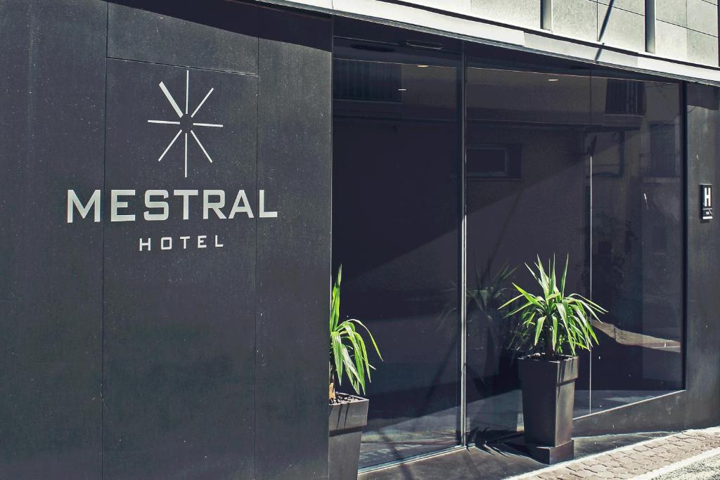 Hotel Mestral Perelló في بيريلو: مبنى فندق معدني أمامه نباتات خزف