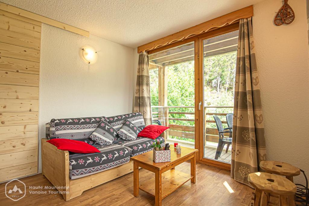 sala de estar con sofá y balcón en Le chalet d'Isis, en Villarodin-Bourget